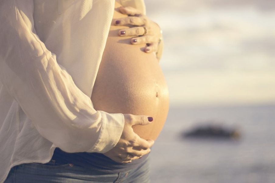 Strie vznikajú v tehotenstve - tehotná žena na obrázku si drží oboma rukami brucho